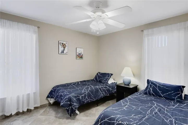 Tiled bedroom featuring ceiling fan