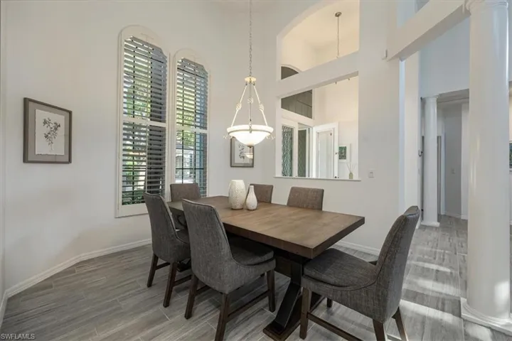 Dining space featuring decorative columns, light wood finished floors, and a high ceiling