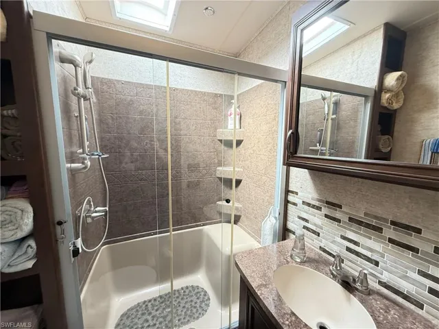 Bathroom with decorative backsplash, vanity, and enclosed tub / shower combo