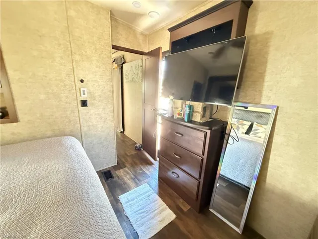 Bedroom with a textured wall and dark wood finished floors