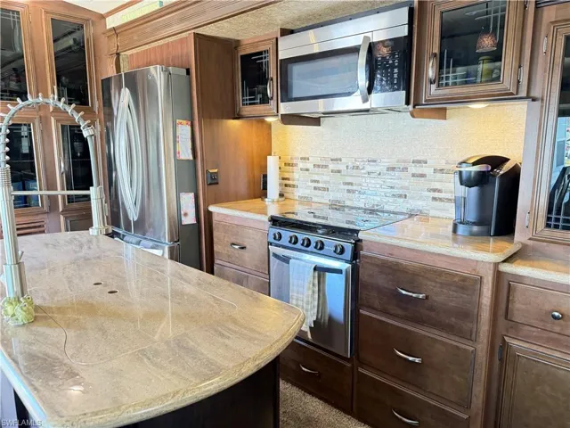 Kitchen with stainless steel appliances, glass fronted cabinets, tasteful backsplash, and a kitchen island