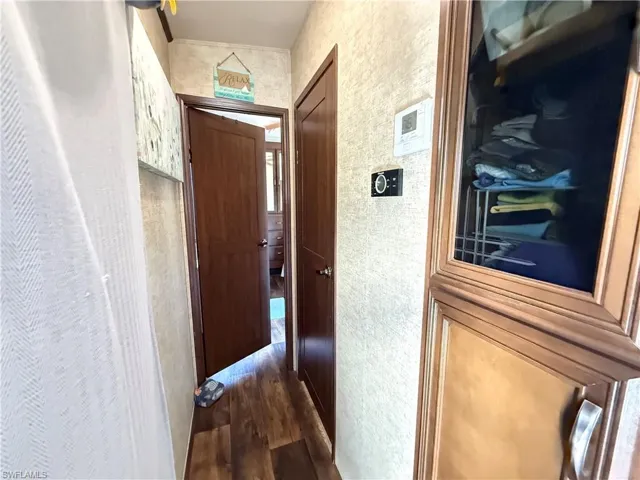 Hallway featuring dark wood-style floors and wallpapered walls