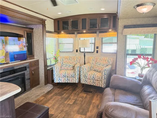 Living area featuring dark wood-style flooring, a glass covered fireplace, and wallpapered walls