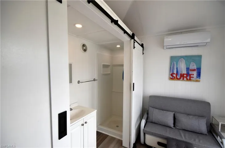 Full bath featuring vanity, wood finished floors, recessed lighting, a wall unit AC, and a shower stall