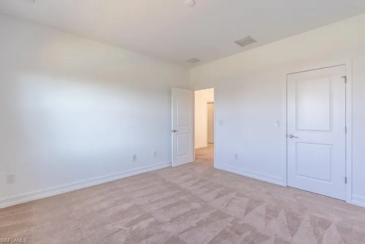 Unfurnished bedroom featuring light carpet and baseboards