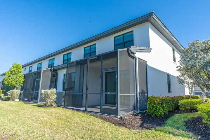 Back of property featuring stucco siding, a sunroom, and a yard