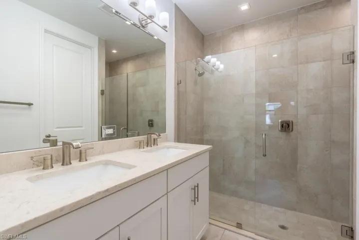 Bathroom with double vanity, a stall shower, and recessed lighting