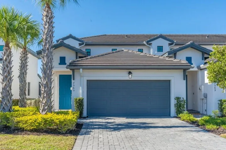 Traditional-style house featuring decorative driveway, a garage, stucco siding, and a tiled roof