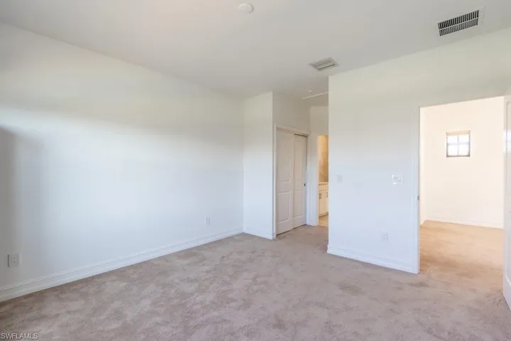 Unfurnished bedroom with light carpet and a closet
