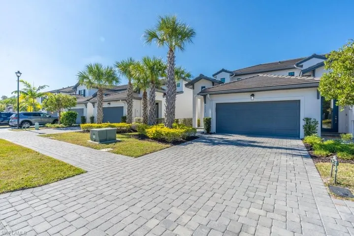 View of front of property with decorative driveway, stucco siding, a garage, and a tile roof