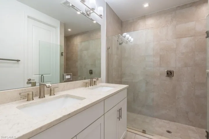 Full bath with double vanity and a tile shower