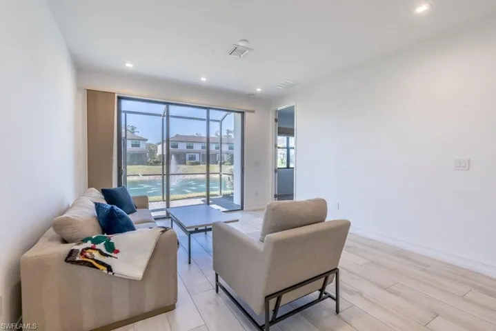 Living room with light wood-style flooring and recessed lighting