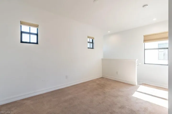 Empty room with plenty of natural light, light colored carpet, and recessed lighting