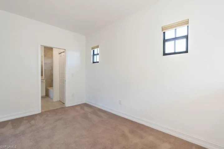 Unfurnished bedroom with light colored carpet and ensuite bath