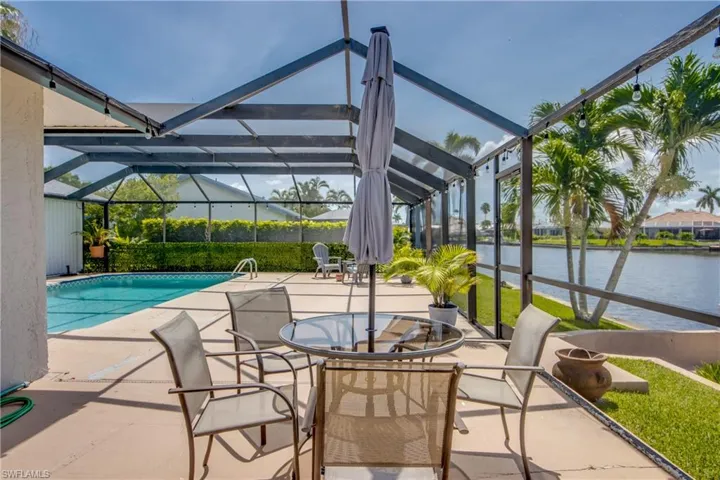Swimming pool with a patio, a water view, and glass enclosure