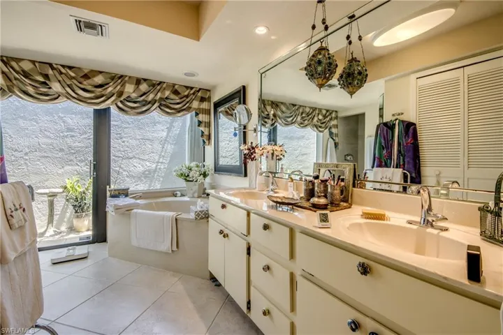 Full bathroom featuring double vanity, tile patterned flooring, a bath, recessed lighting, and a closet