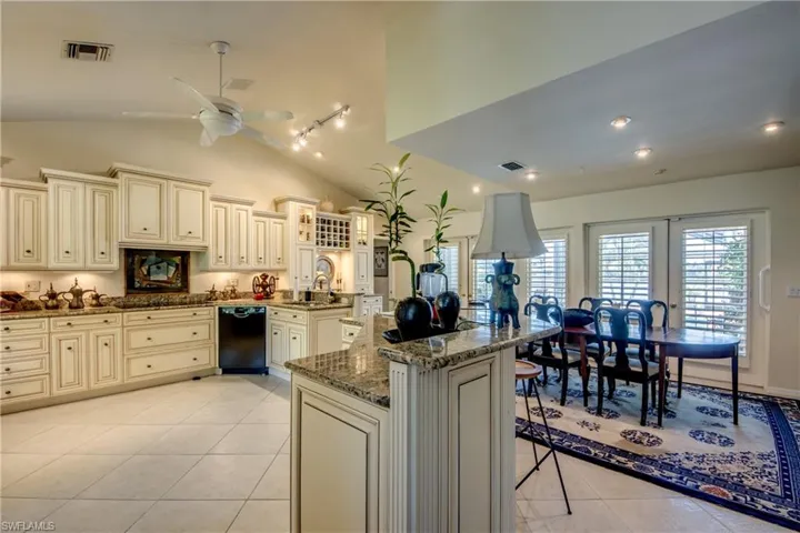 Kitchen featuring cream cabinets, black dishwasher, ceiling fan, light tile patterned flooring, and dark stone countertops
