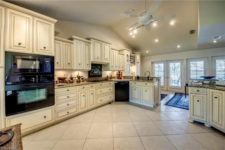 Kitchen featuring cream cabinetry, black appliances, a peninsula, lofted ceiling, and ceiling fan
