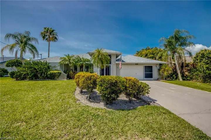 View of front of property featuring driveway, a front lawn, and stucco siding