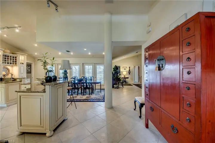Kitchen featuring cream cabinetry, rail lighting, dark stone countertops, a kitchen island, and light tile patterned floors