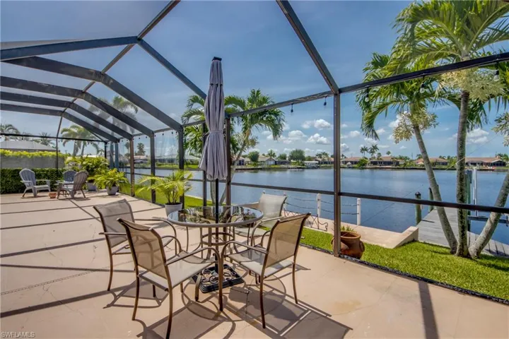 View of patio featuring a water view and glass enclosure