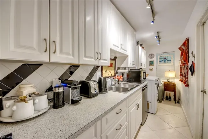 Kitchen featuring stainless steel appliances, white cabinets, light tile patterned floors, and track lighting