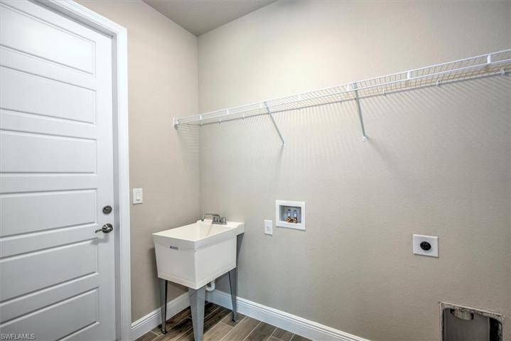 Washer and dryer hook up, shelving and wash sink in laundry room.