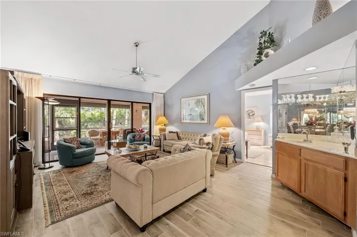 Living area featuring light wood finished floors, high vaulted ceiling, and a ceiling fan
