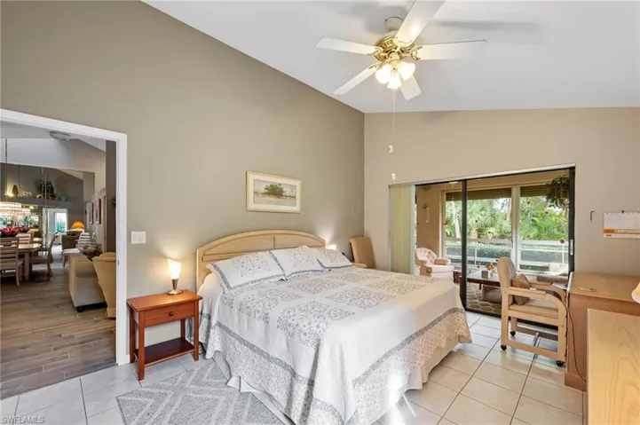 Bedroom with access to outside, a ceiling fan, high vaulted ceiling, and light tile patterned flooring