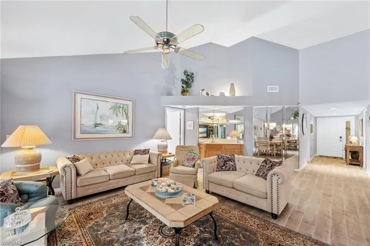 Living room with wood finished floors, high vaulted ceiling, and ceiling fan