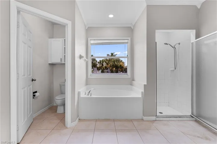 Bathroom with a garden tub, a shower stall, crown molding, and tile patterned flooring