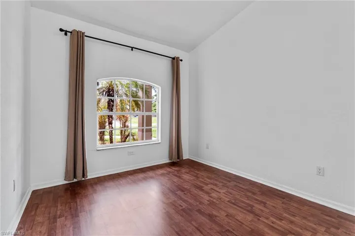 Empty room with lofted ceiling and wood finished floors