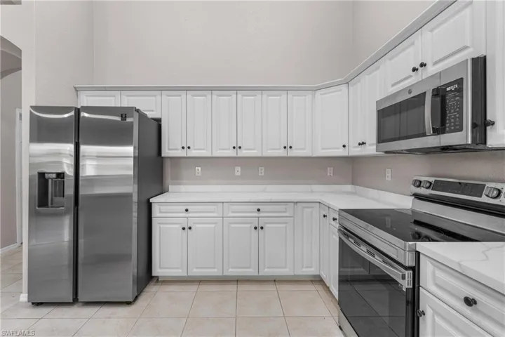 Kitchen with stainless steel appliances, arched walkways, and white cabinetry