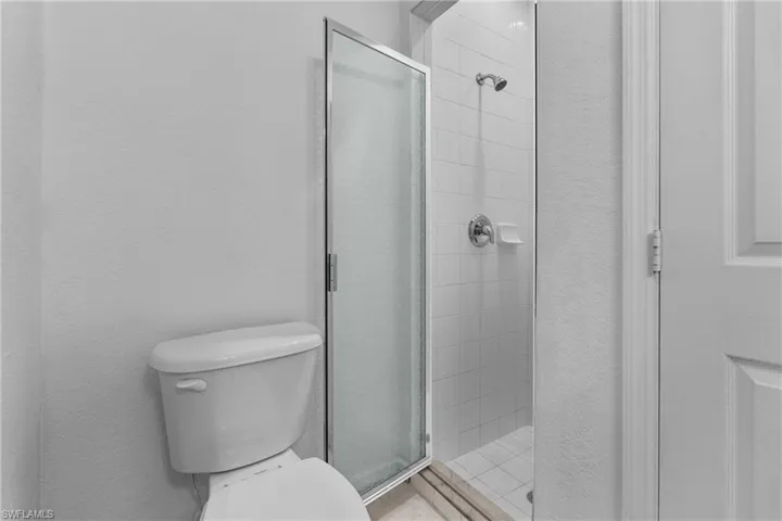 Full bath with a shower stall and a textured wall