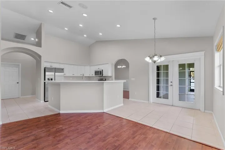 Kitchen with appliances with stainless steel finishes, arched walkways, a chandelier, light wood-style floors, and light countertops