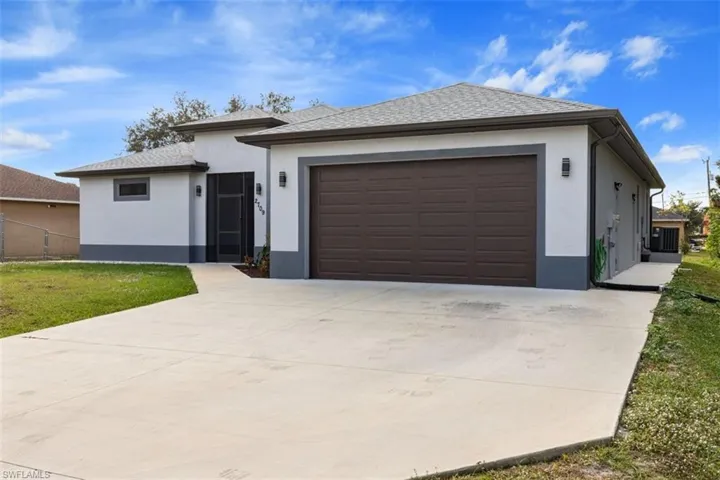 View of front of home featuring stucco siding, concrete driveway, a front yard, and a garage