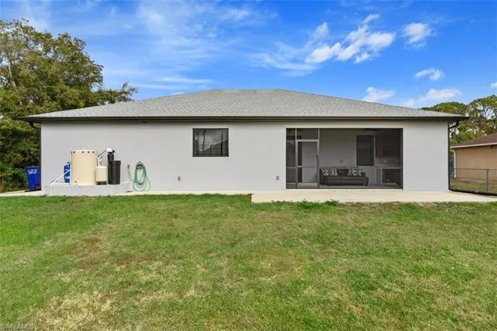 Back of property featuring a lawn, stucco siding, a sunroom, and roof with shingles