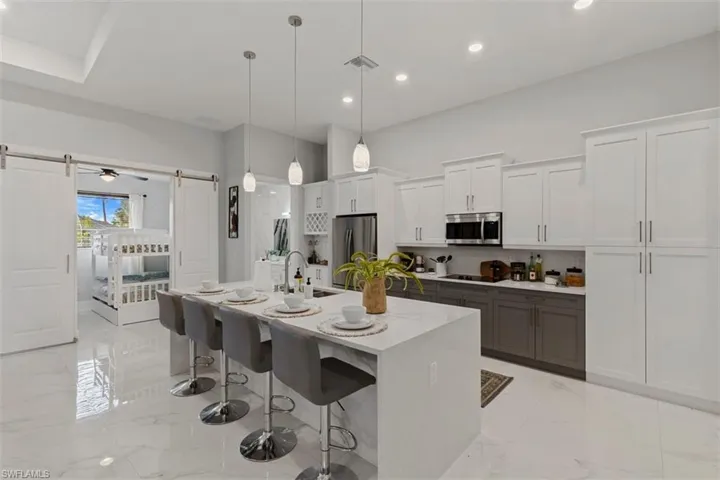 Kitchen with white cabinets, a kitchen bar, recessed lighting, pendant lighting, and an island with sink