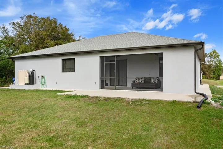 Back of property with a lawn, a ceiling fan, stucco siding, and a patio area