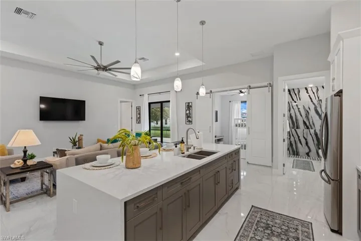 Kitchen featuring a barn door, hanging light fixtures, a raised ceiling, freestanding refrigerator, and ceiling fan