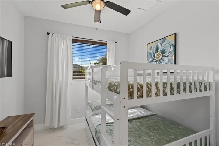 Bedroom with light marble finish floors and ceiling fan