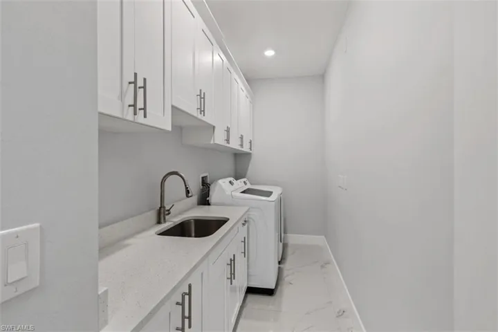 Washroom with light marble finish flooring, cabinet space, separate washer and dryer, and recessed lighting