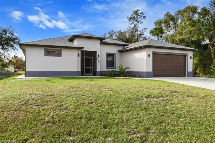 Prairie-style home with stucco siding, a front lawn, a garage, and driveway