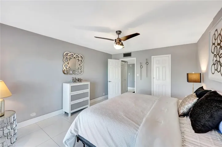 Tiled bedroom with a ceiling fan and a closet