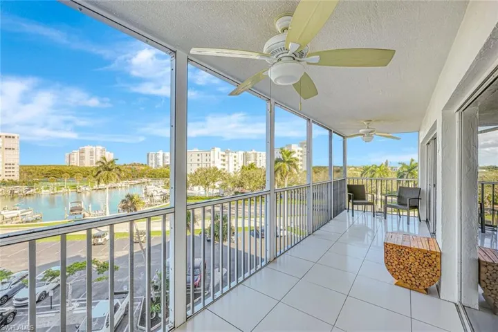 Unfurnished sunroom featuring a water view, a balcony, and a ceiling fan