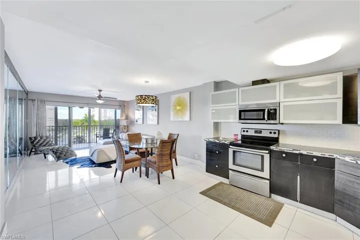 Kitchen featuring stainless steel appliances, decorative backsplash, white cabinetry, ceiling fan, and light tile patterned flooring