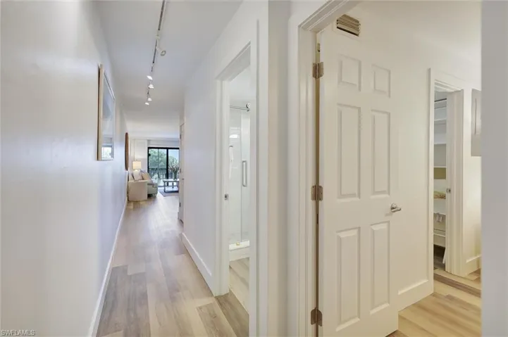Hallway featuring light wood-style floors and track lighting