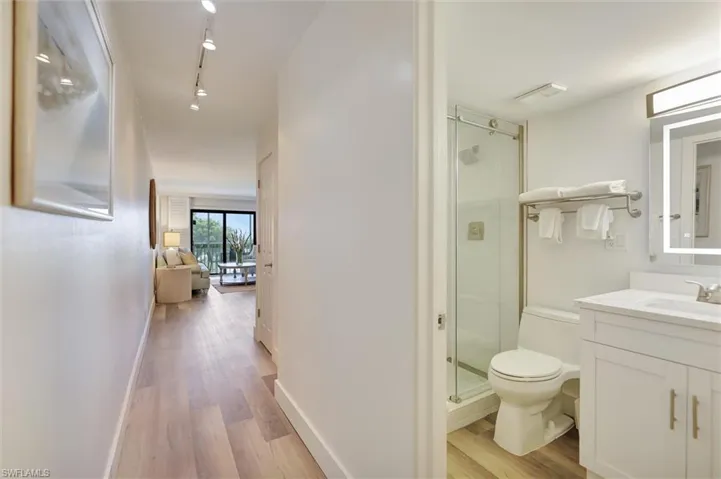 Bathroom featuring a stall shower, light wood finished floors, vanity, and track lighting