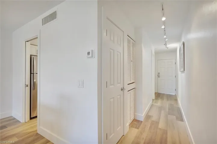 Hallway featuring light wood-style flooring and track lighting