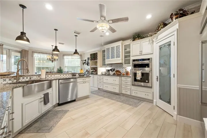 Kitchen with ceiling fan with notable chandelier, a sink, ornamental molding, and stainless steel appliances
